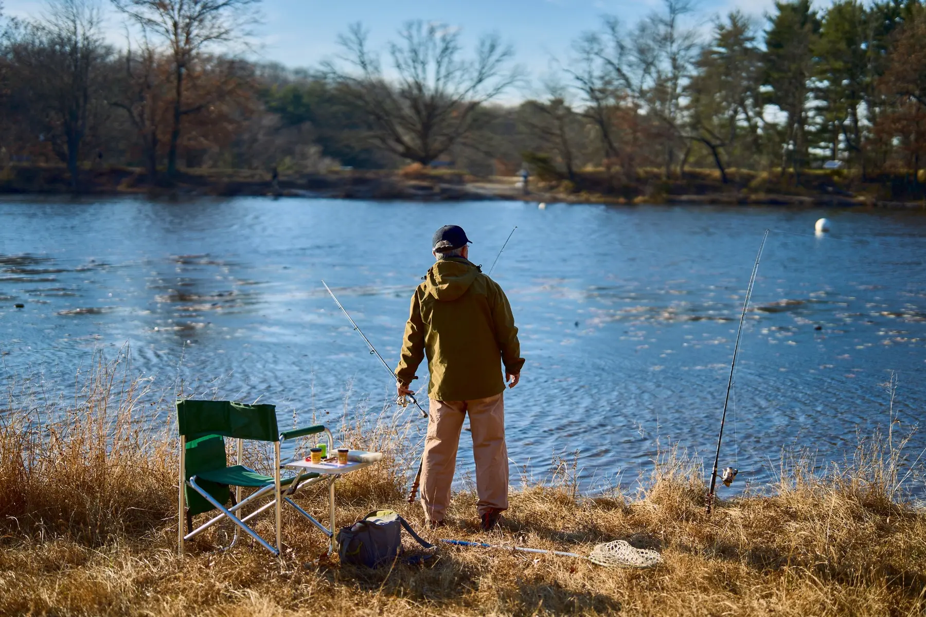 Angler mit mehreren Ruten am Ufer eines Sees